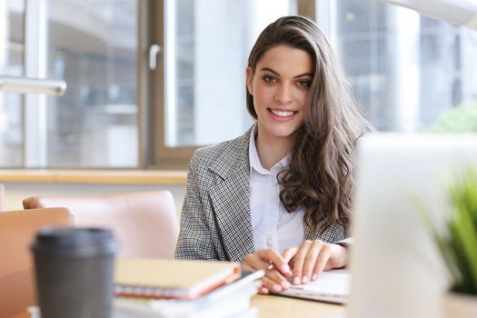 Portrait of a pretty female student with laptop in library