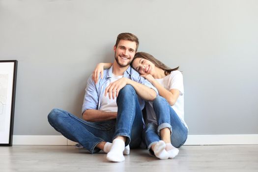 The happy couple sitting on the background of the gray wall