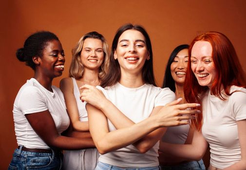 young pretty caucasian, afro, scandinavian woman posing cheerful together on brown background, lifestyle diverse nationality people concept close up