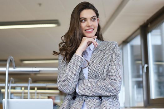 Attractive businesswoman standing near desk in the office