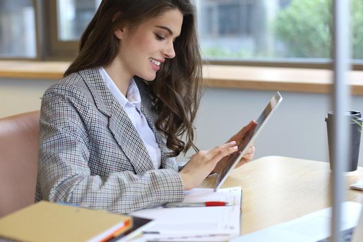 Young smiling businesswoman in office working on digital tablet