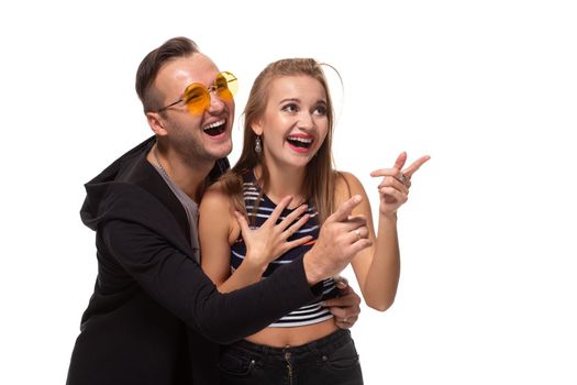 Portrait of the happy couple looking and pointing into the distance, isolated on white background. Emotional young couple laughing at something