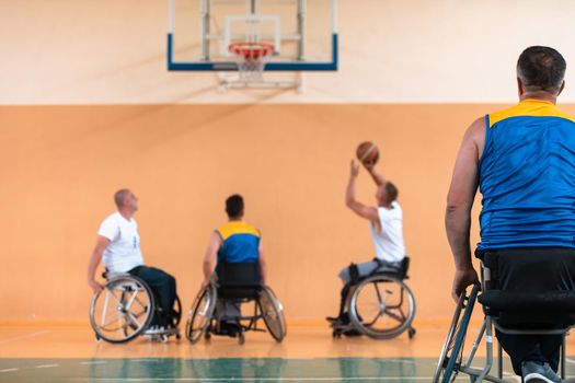 Disabled War or work veterans mixed race and age basketball teams in wheelchairs playing a training match in a sports gym hall. Handicapped people rehabilitation and inclusion concept.Hi quality photo