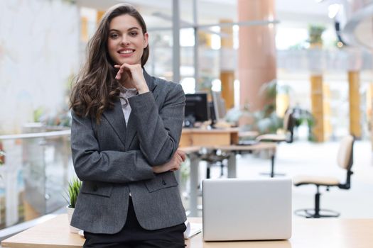 Attractive businesswoman standing near desk in the office
