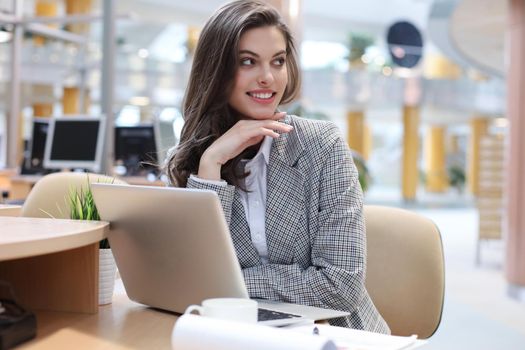 Portrait of a young brunette business woman using laptop at office