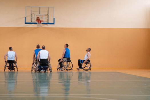 Disabled War veterans mixed race opposing basketball teams in wheelchairs photographed in action while playing an important match in a modern hall. High quality photo