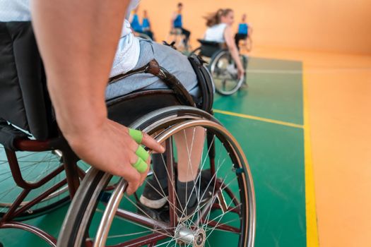 Close up photo of wheelchairs and handicapped war veterans playing basketball on the court. Selective focus 