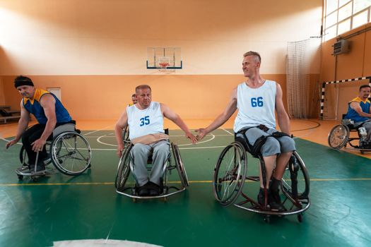 Disabled War or work veterans mixed race and age basketball teams in wheelchairs playing a training match in a sports gym hall. Handicapped people rehabilitation and inclusion concept.Hi quality photo