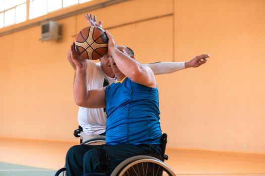 Disabled War or work veterans mixed race and age basketball teams in wheelchairs playing a training match in a sports gym hall. Handicapped people rehabilitation and inclusion concept.Hi quality photo