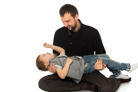 Father and son frolic on the floor. Dad keeps son in his hands - Isolated on white background