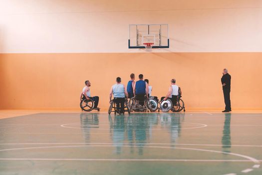 Disabled War veterans mixed race opposing basketball teams in wheelchairs photographed in action while playing an important match in a modern hall. High quality photo