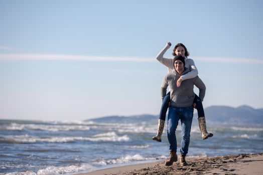 Men Giving Piggy Back Rides his girlfriend At Sunset By The Sea, autumn time