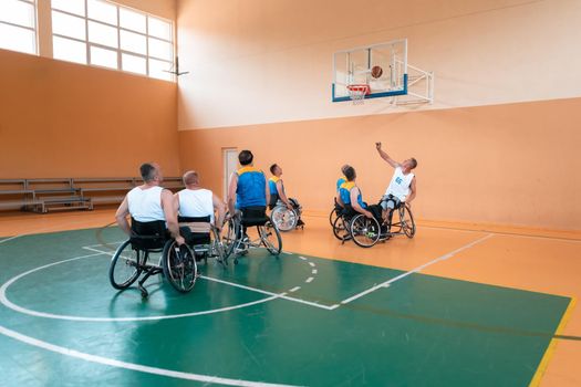 Disabled War or work veterans mixed race and age basketball teams in wheelchairs playing a training match in a sports gym hall. Handicapped people rehabilitation and inclusion concept.Hi quality photo