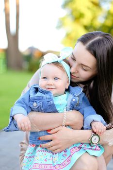 Young european woman holding little daughter wearing jeans jacket. Concept of motherhood and children.