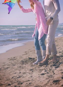 Family with little daughter resting and having fun with a kite at beach during autumn day colored filter