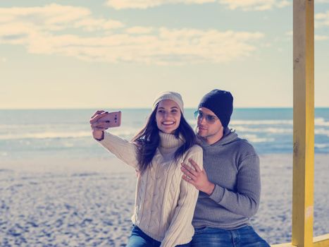 Very Happy Couple In Love Taking Selfie On The Beach in autmun day