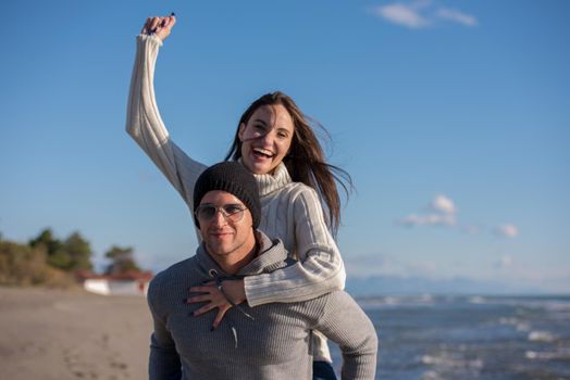 Men Giving Piggy Back Rides his girlfriend At Sunset By The Sea, autumn time