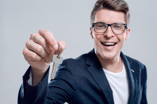 male adult businessman in a suit giving a keys, isolated close-up, indoor