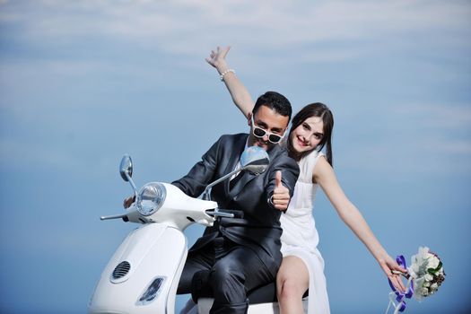 wedding sce of bride and groom just married couple on the beach ride white scooter and have fun