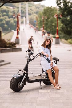 Young beautiful woman and an electric scooter, modern girl, new generation, electric transport, ecological transport