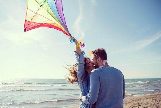 Young Couple having fun and Playing With A Kite On The Beach at autumn day filter