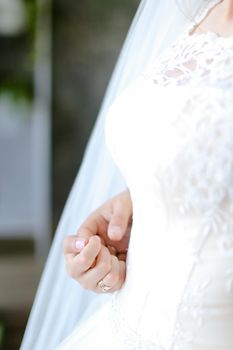 Closeup bridal white dress and hand. Concept of wedding photo session.