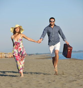 couple on beach with travel bag representing freedom and funy honeymoon concept