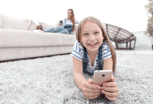 cute little girl with smartphone lying on the carpet in the living room.photo with copy space