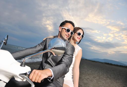 wedding sce of bride and groom just married couple on the beach ride white scooter and have fun