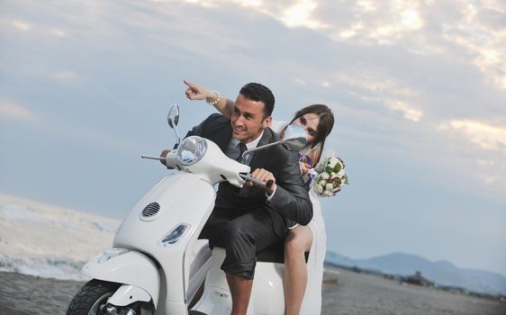 wedding sce of bride and groom just married couple on the beach ride white scooter and have fun