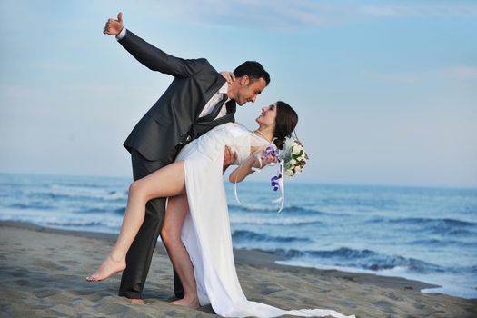 happy just married young couple celebrating and have fun at beautiful beach sunset