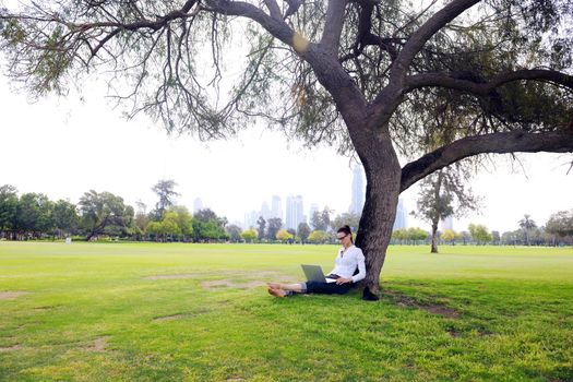 happy young student woman with laptop in city park study