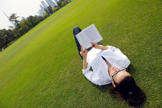 Young student woman reading a book and study in the park