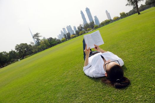 Young student woman reading a book and study in the park