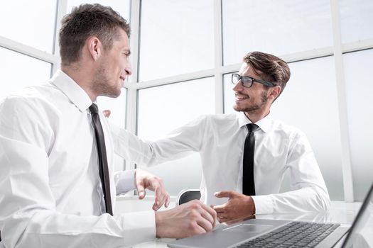 Two businessmen are sitting in the office and discussing the conclusion of a new deal