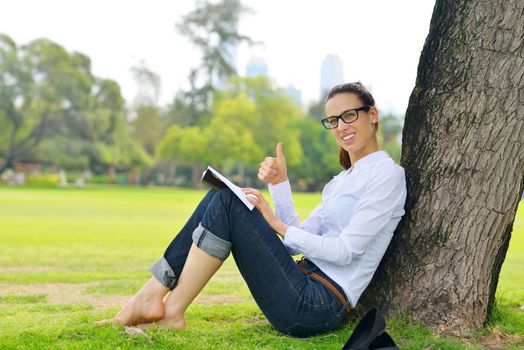 Young student woman reading a book and study in the park