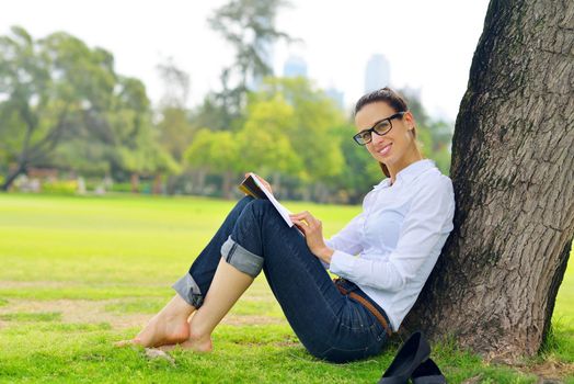 Young student woman reading a book and study in the park