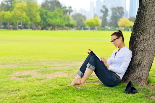 Young student woman reading a book and study in the park