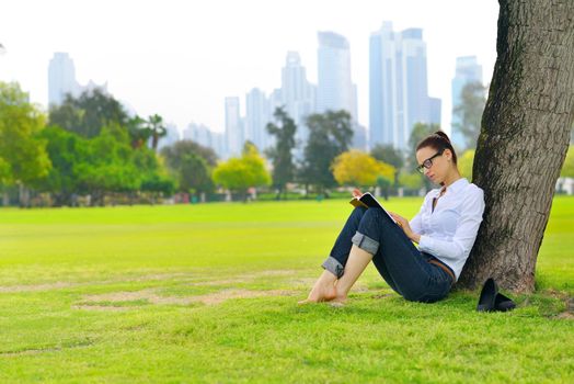 Young student woman reading a book and study in the park