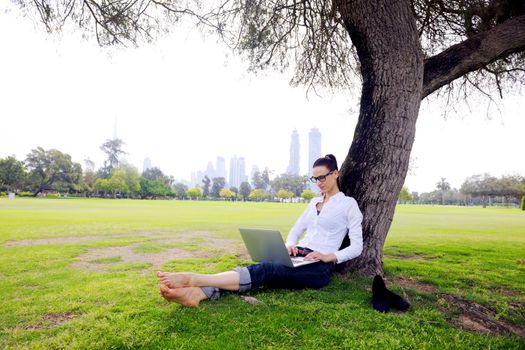 happy young student woman with laptop in city park study