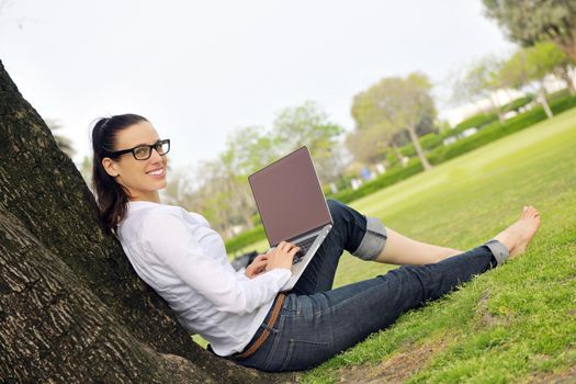 happy young student woman with laptop in city park study