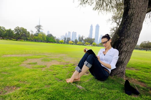 Young student woman reading a book and study in the park