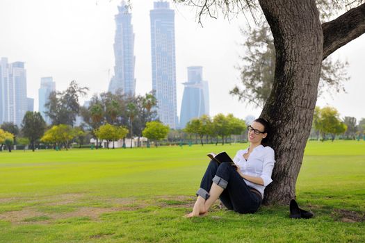 Young student woman reading a book and study in the park