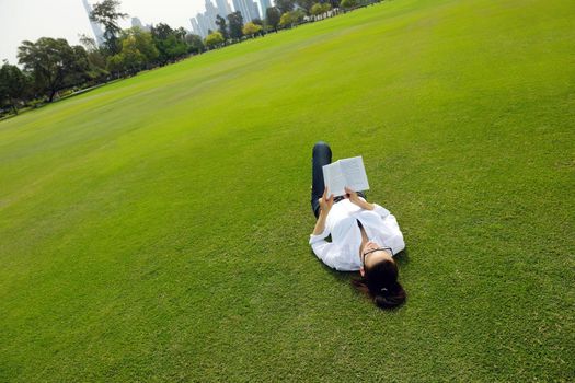 Young student woman reading a book and study in the park