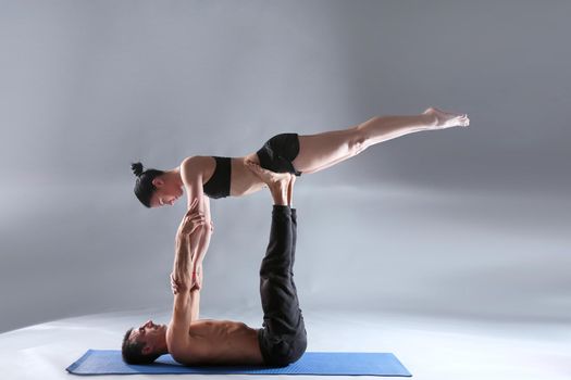 Young couple practicing acro yoga on mat in studio together. Acroyoga. Couple yoga. Partner yoga