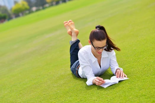 Young student woman reading a book and study in the park