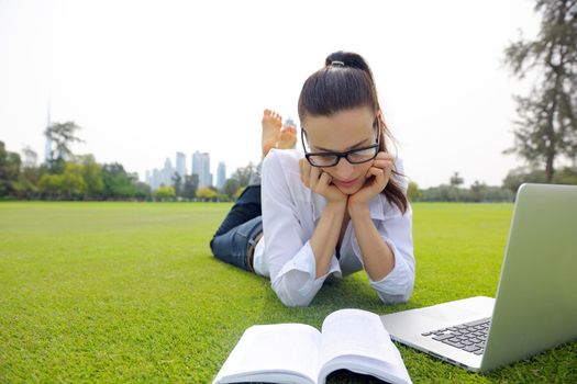 happy young student woman with laptop in city park study