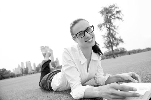 Young student woman reading a book and study in the park