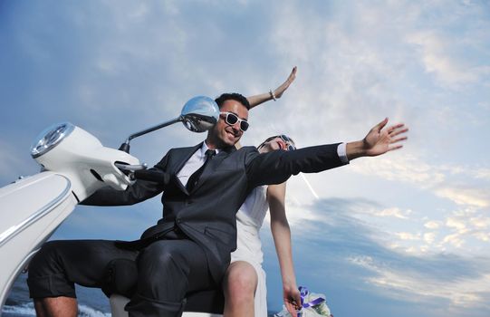 wedding sce of bride and groom just married couple on the beach ride white scooter and have fun