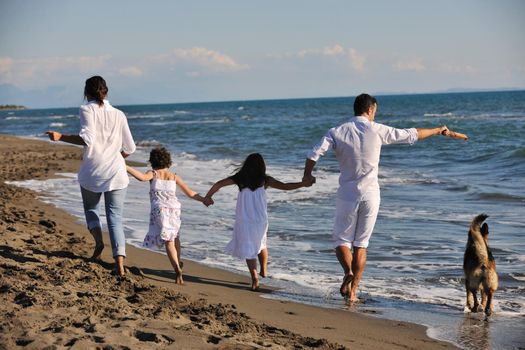 happy young family in white clothing have fun and play with beautiful dog at vacations on beautiful beach 